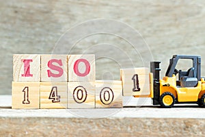 Toy forklift hold block 1 to complete word ISO 14001 on wood background