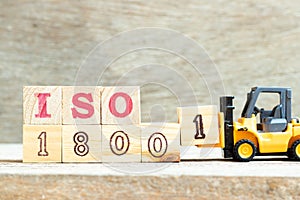 Toy forklift hold block 1 to complete word iso 18001 on wood background