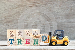 Toy forklift hold block d to complete word 2020 trend on wood background