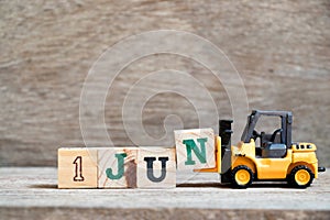 Toy forklift hold block N to word 1 jun on wood background Concept for calendar date in month June