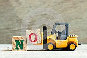 Toy forklift hold block o to complete word no on wood background