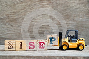 Toy forklift hold block P to complete word 21 sep on wood background Concept for calendar date in month September