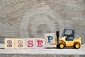 Toy forklift hold block P to complete word 22 sep on wood background Concept for calendar date in month September