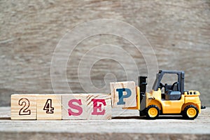 Toy forklift hold block P to complete word 24 sep on wood background Concept for calendar date in month September