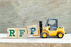 Toy forklift hold block P to complete word RFP (Abbreviation of request for proposal) on wood background