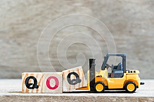 Toy forklift hold block q in word qoq abbreviation of quarter on quarter on wood background
