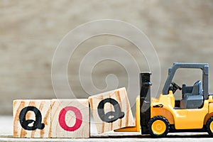 Toy forklift hold block Q in word qoq abbreviation of quarter on quarter on wood background