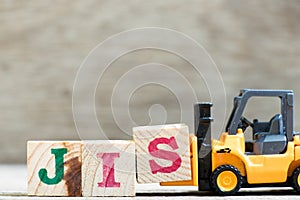 Toy forklift hold block s in word JIS abbreviation of Just in sequence on wood background