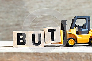 Toy forklift hold block t to complete word but on wood background