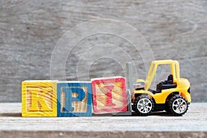 Toy forklift hold color block I to complete word KPI Abbreviation of Key performance indicator on wood background