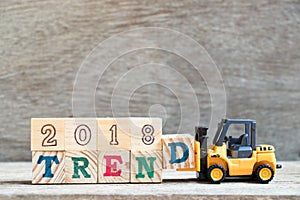 Toy forklift hold letter block d to complete word 2018 trend on wood background