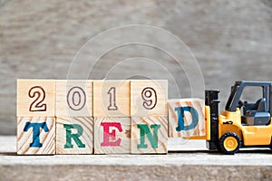 Toy forklift hold letter block d to word 2019 trend on wood background