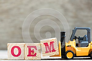 Toy forklift hold letter block M in word OEM abbreviation of original equipment manufacturer