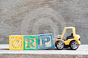 Toy forklift hold block P to complete word CRP abbreviation of C-Reactive Protein Test on wood background