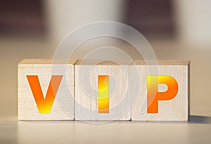 Toy forklift hold letter block P to complete word VIP on wood background