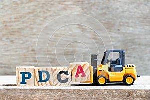 Toy forklift hold letter block A to complete word PDCA Plan, Do, Check, Act