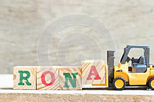 Toy forklift hold block a to complete word RONA Abbreviation of Return on net assets on wood background photo