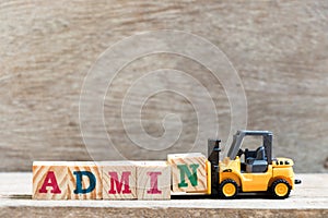 Toy forklift hold letter N in word admin on wood background