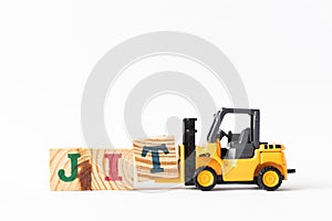 Toy forklift hold wood block T to complete word JIT Abbreviation of Just in time on white background