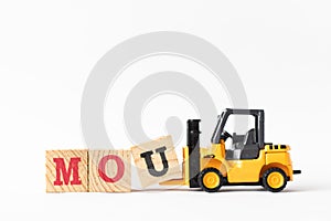 Toy forklift hold wood block U to complete word MOU Abbreviation of memorandum of understanding on white background