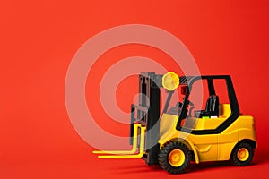 Toy forklift on red background. Logistics and wholesale concept