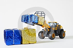 Toy forklift works with yellow and blue colored boxes. Concept of humanitarian aid to Ukrainians. Concept of delivering gifts to