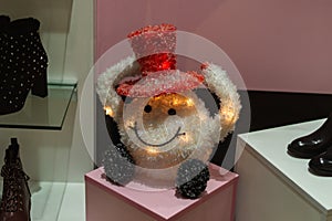 Toy in the form of a ball in a hat on the shop window among the shoes
