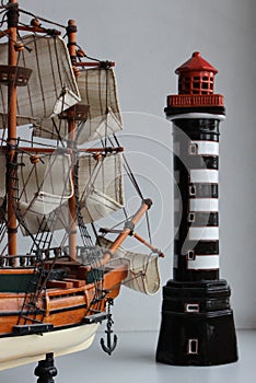 Toy Frigate With Fabric Sails Turned Bow To A Miniature Lighthouse Stock Photo