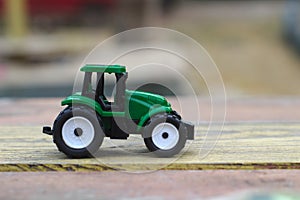 toy green tractor on a yellow-red wooden table