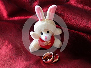 Toy hare and two wedding rings on a red cloth