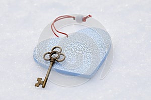 Toy heart and key on the snow, concept on the theme of unrequited love or metaphor of the key to the heart, background for