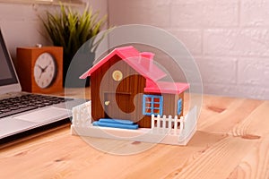 Toy house on desk with laptop computer, The concept of buying a dream home for beginners working