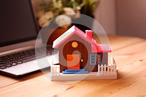 Toy house on desk with laptop computer, The concept of buying a dream home for beginners working