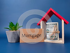 Toy house,green plant and banknotes with the word Mortgage
