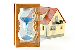 Toy house and hourglass with blue sand