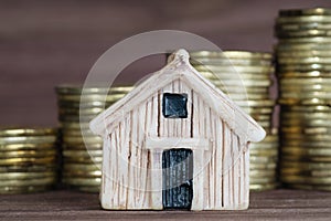 Toy house model against coins stacks background