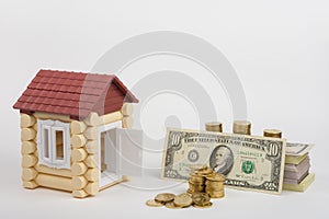 Toy house near money is to purchase a pack of bills and a stack of coins