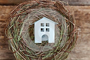 Toy house in nest on wooden background