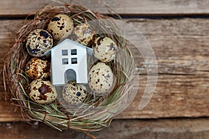 Toy house in nest on wooden background