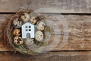 Toy house in nest on wooden background