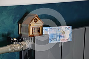 A toy house and Russian banknotes lie on the radiator of the heating system, heating the home. fuel crisis