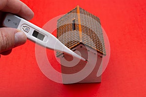 Toy house, thermometer on red color.  Home quarantine concept