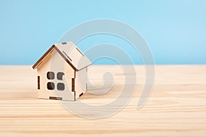 Toy house on wooden table on blue baclground. Mortgage property insurance dream home concept. Close-up view of small house model