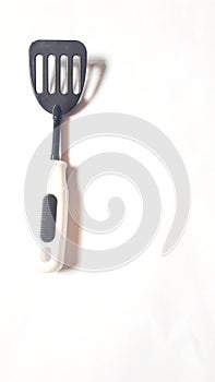 Toy kitchen utensils: black white spatula, plastic spoon on white backround