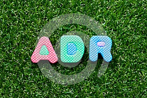 Toy letter in word ADR Abbreviation of Adverse drug reaction on green grass background