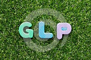 Toy letter in word GLP Abbreviation of Good laboratory practice on green grass background