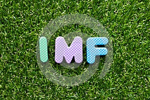Toy letter in word IMF abbreviation of International Monetary Fund on green grass background