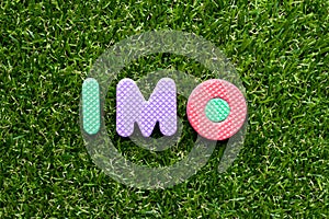 Toy letter in word  IMO Abbreviation of in my opinion on green grass background