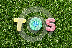 Toy letter in word TOS abbreviation of Terms Of Service on green grass background photo