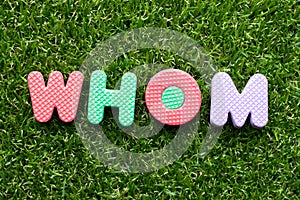 Toy letter in word whom on green grass background